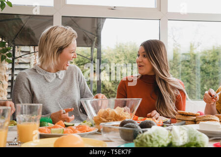 Two female friends enjoying talking while preparing their dinner. Stock Photo
