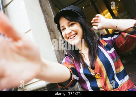 Happy laughing mixed race woman in a multi-colored striped dress makes selfie Stock Photo