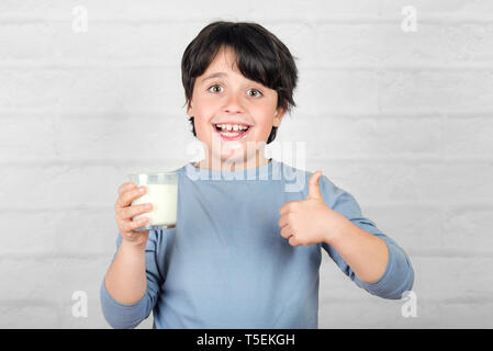 smiling child drinking milk against brick background Stock Photo