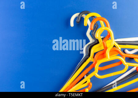 Colored hangers stacked on blue background with place for text, minimalist style Stock Photo