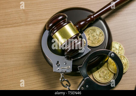 Gavel and handcuffs with bitcoins on wooden desk. Cryptocurrency legal concept. Stock Photo