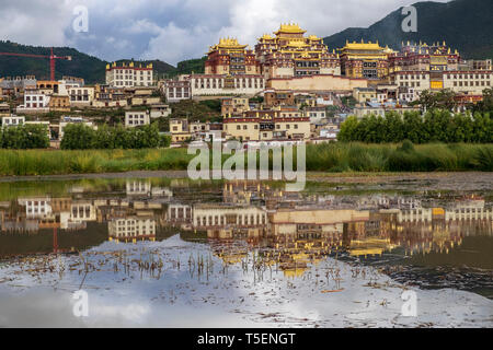 Songzanlin Tibetan Buddhist Monastery reflected in sacred lake, Shangri-La, Yunnan Province, China Stock Photo