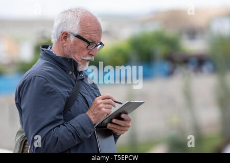 Cordoba, Spain - April 23, 2019: Senior man is taking notes while sightseeing Stock Photo