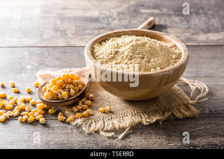 Corn flour in bowl on wooden table Stock Photo