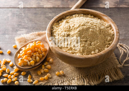 Corn flour in bowl on wooden table Stock Photo