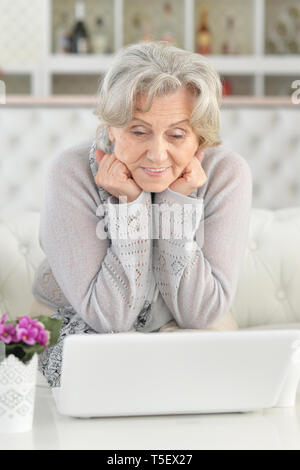 Senior woman using laptop while sitting on sofa Stock Photo