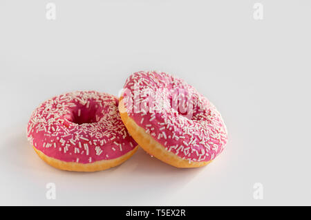 Two donuts with pink icing on a white background. Stock Photo