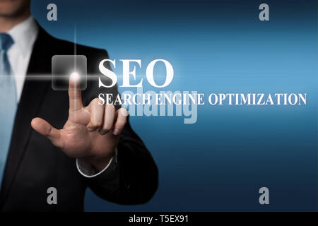business concept - businessman presses virtual touchscreen button - SEO Search Engine Optimization Stock Photo