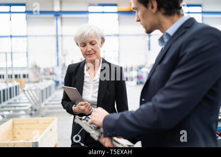 Businessman and senior businesswoman examining workpiece in a factory Stock Photo