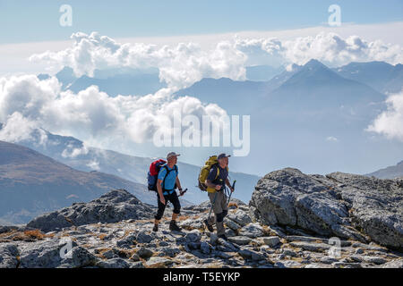 Aussois (south-eastern France): two hikers crossing a wooden footbridge over a stream in the direction of the Aussois Pass, in the Vanoise National Pa Stock Photo