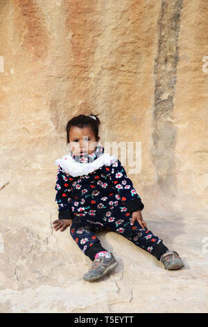 A cute Bedouin girl sitting by the rock in Jordan's Little Petra. Stock Photo