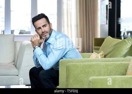Thoughtful businessman sitting in hotel lobby Stock Photo