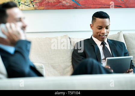 Businessman using digital tablet in hotel lobby Stock Photo
