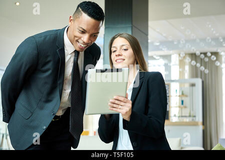 Business people using a digital tablet in hotel lobby Stock Photo