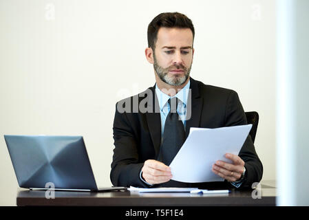 Businessman reading documents in office Stock Photo