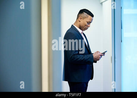 Businessman using smart phone in hotel lobby Stock Photo