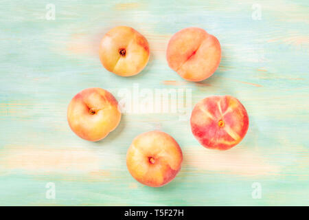 Vibrant organic flat saturn peaches, shot from above on a teal background, forming a circular frame with a place for text Stock Photo