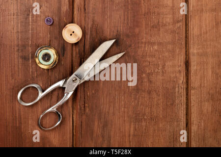 Vintage scissors and buttons, shot from the top on a dark rustic wooden background with a place for text Stock Photo