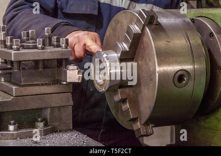 Blue-collar machine operator working with lathe machine in a factory. Stock Photo