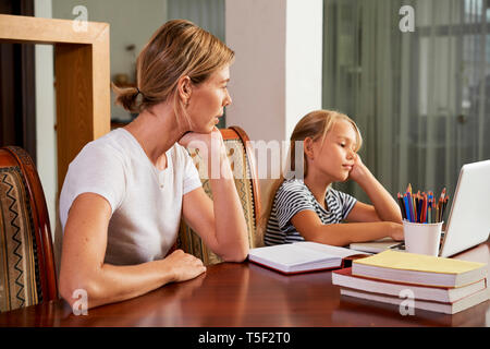 Mother looking at her daughter doing homework Stock Photo