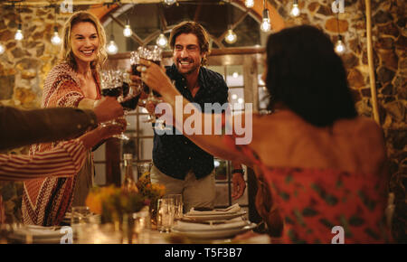 Friends making big party in the night. Group of people toasting wine during a dinner party. Stock Photo