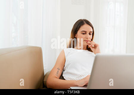 Pensive woman working on laptop Stock Photo