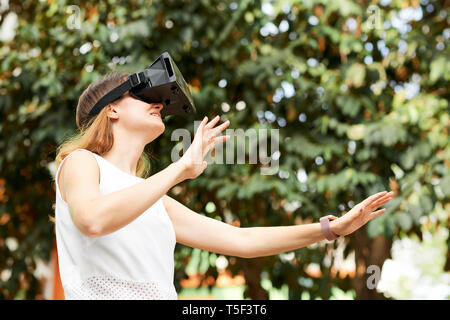 Woman in vr goggles standing outdoors Stock Photo