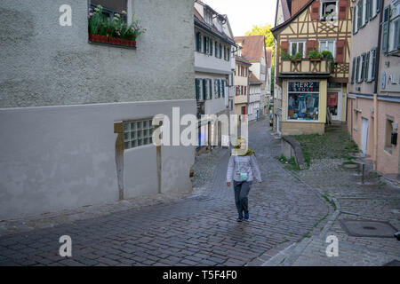 TUBINGEN/GERMANY-JULY 30 2019: A Moslem young girl walking on the path near Nice old half-timbered fachwerk houses Stock Photo
