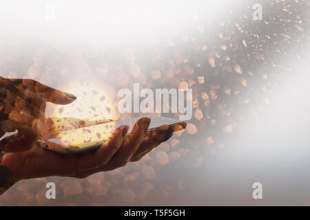 Female hand holding a smartphone with abstract glowing plasma ball and flying fiery highlight. Double exposure Stock Photo