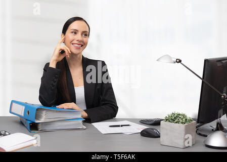 Female accountant sitting at desk in office. Portrait of young smiling bookkeeper Stock Photo