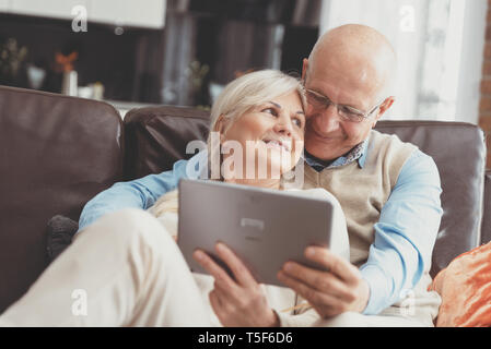 Senior couple with digital tablet at home. Grandparents using social media. Stock Photo