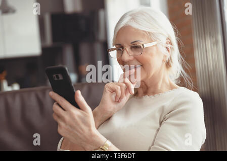 Beautiful senior woman texting at home. The pensioner uses social media Stock Photo