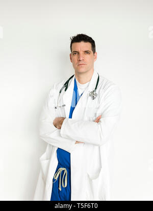 Medical doctor in white coat and scrubs standing with arms folded. Stock Photo