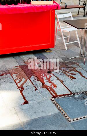 Broken bottle of red vine - fragments of glass on city pavement. Stock Photo