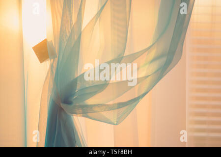 Sun at sunset light through the thin curtains on the window with blinds Stock Photo