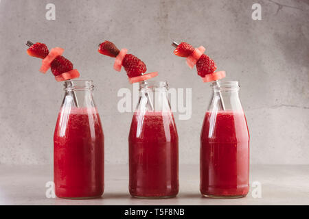 Side view of three glass bottles of fresh red berry juice Stock Photo