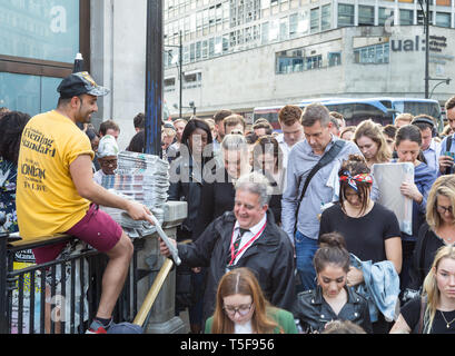 Vendors distribute copies of Evening Standard newspaper at rush hour to commuters crowding into Oxford Circus underground station in London Stock Photo