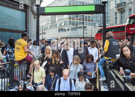 Vendors distribute copies of Evening Standard newspaper at rush hour to commuters crowding into Oxford Circus underground station in London Stock Photo