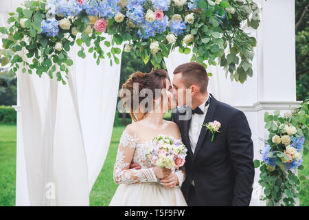 Soulful photo of the newlyweds hugging and kissing each other during the wedding ceremony Stock Photo