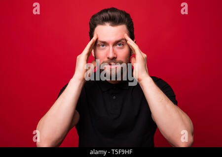 Young man having a stress headache pressing forehead isolated on red background Stock Photo