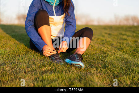Young woman tying shoelace of sneakers to make outwork training running. Fitness and healthy lifestyle Stock Photo