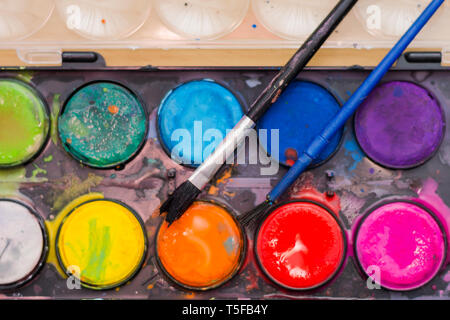 A set of used watercolor paints with brushes close-up Stock Photo