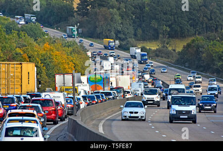 Rush hour on M25 UK motorway queue of cars trucks & lorries in traffic jam in hilly rural countryside section of London orbital highway England UK Stock Photo