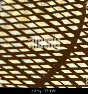 Abstract background  image created by sunshine on wicker cane chair casting shadow of curved pattern shapes on beige indoor carpet  texture surface UK Stock Photo
