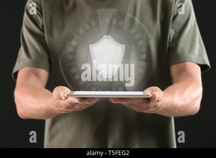 Man with tablet PC and shield icon on dark background. Data security concept Stock Photo