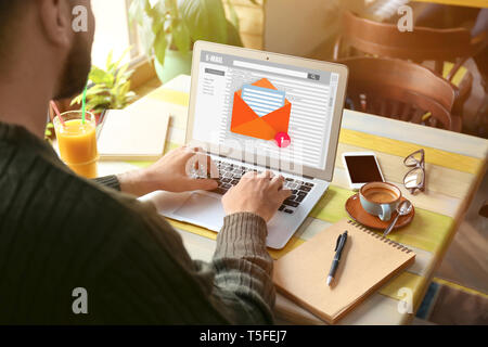 Young man with laptop checking an email in cafe Stock Photo