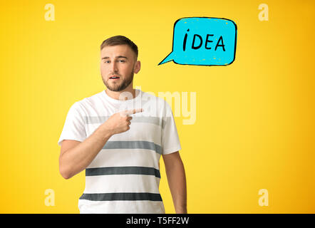 Thoughtful man pointing at word IDEA on color background Stock Photo