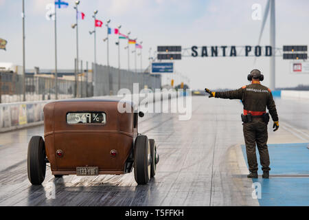 A marshal makes a vintage hot rod car wait in the staging area of the drag strip during the VHRA Vintage Nationals, Santa Pod Raceway