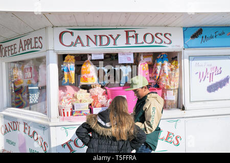 A young girl and boy counting small change money at a Candy Floss and confectionery stall on Brighton Palace Pier, East Sussex, England, UK