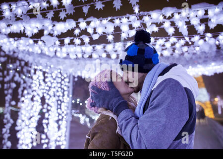 Happy young couple kissing in winter decoration Stock Photo